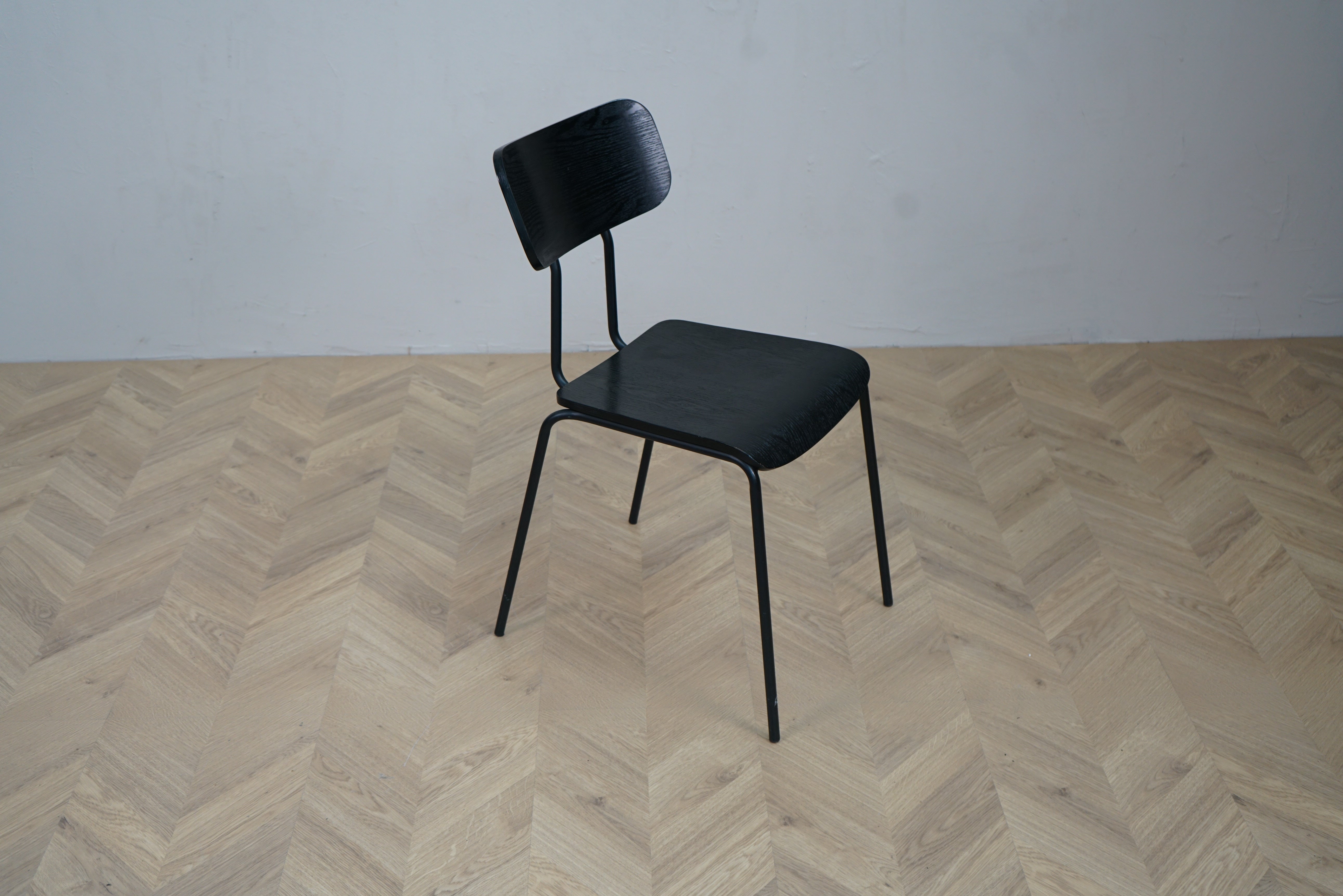 Ellos kantinestol i sort formbøjet askefiner set fra siden med mat sort stålstel.